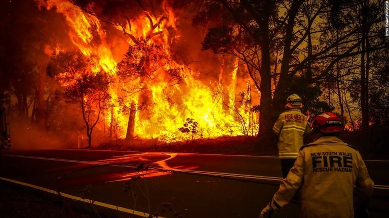 家屋の近くで発生している森林火災を注視する隊員ら/David Gray/Getty Images
