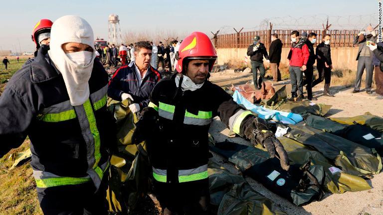 遺体の収容袋を運ぶ当局者/Ebrahim Noroozi/AP