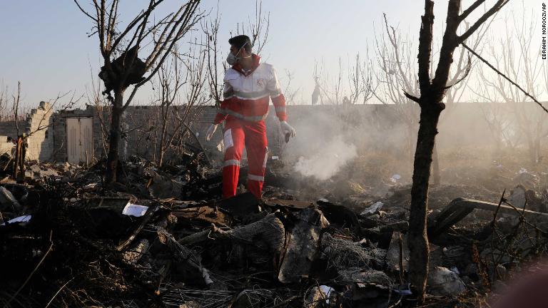 機体の残骸の中に立つ救助隊員/Ebrahim Noroozi/AP