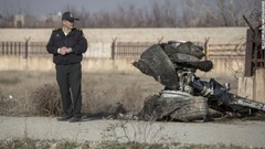 飛行機の残骸の近くに立つ当局者