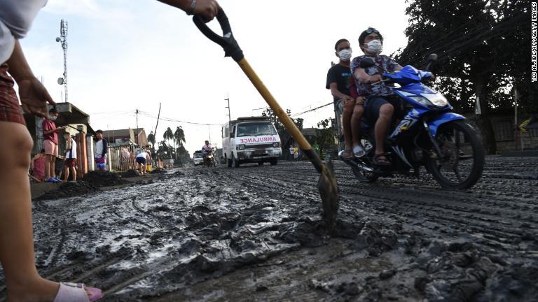 住民がショベルで泥や灰を除去する様子/Ted Aljibe/AFP/Getty Images