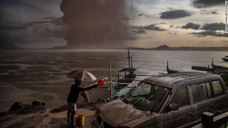 灰に覆われた車を水で洗う様子/Ezra Acayan/Getty Images