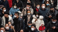 マスクをして電車に乗り込む人々＝北京市