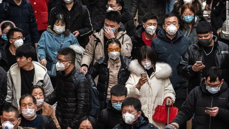 マスクをして電車に乗り込む人々＝北京市/Kevin Frayer/Getty Images