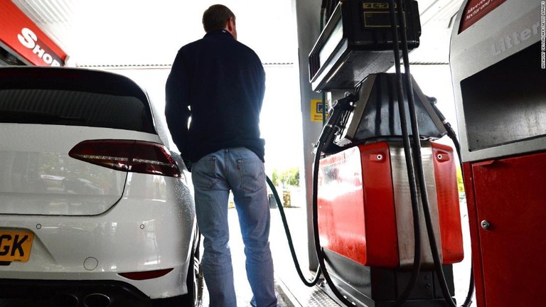 英国内のガソリンスタンドで給油する男性/ANTHONY DEVLIN/AFP/Getty Images