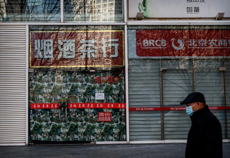 北京で閉店している銀行の支店前を歩く男性＝１０日/Kevin Frayer/Getty Images