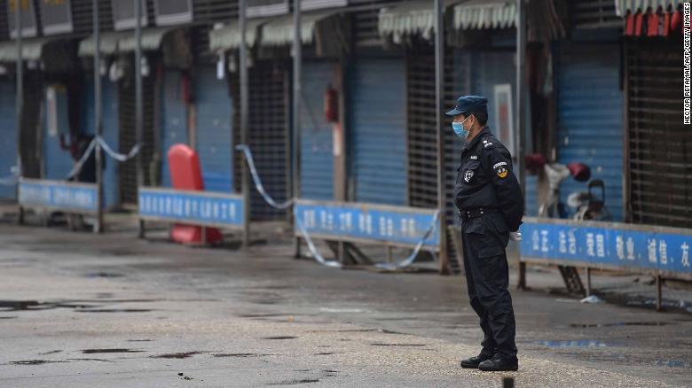 新型コロナウイルスが見つかった武漢の海鮮市場の外に立つ警備員/HECTOR RETAMAL/AFP/Getty Images