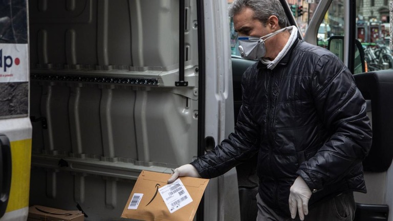 マスクをしてアマゾンの小包を扱う配達員＝１１日/Emanuele Cremaschi/Getty Images