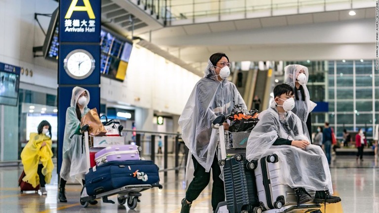 マスクを着用して香港の空港内を移動する旅行者/Anthony Kwan/Getty Images AsiaPac/Getty Images