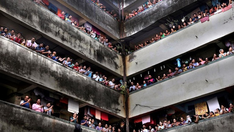 集合住宅のバルコニーから拍手を送る人々＝２２日、ムンバイ/Rafiq Maqbool/AP