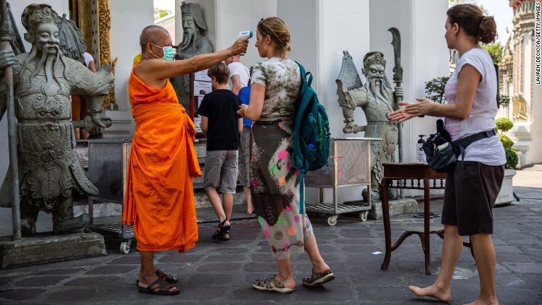 寺院に入る前に観光客の体温を調べる僧侶＝１３日、タイ・バンコク/Lauren DeCicca/Getty Images