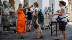 寺院に入る前に観光客の体温を調べる僧侶＝１３日、タイ・バンコク