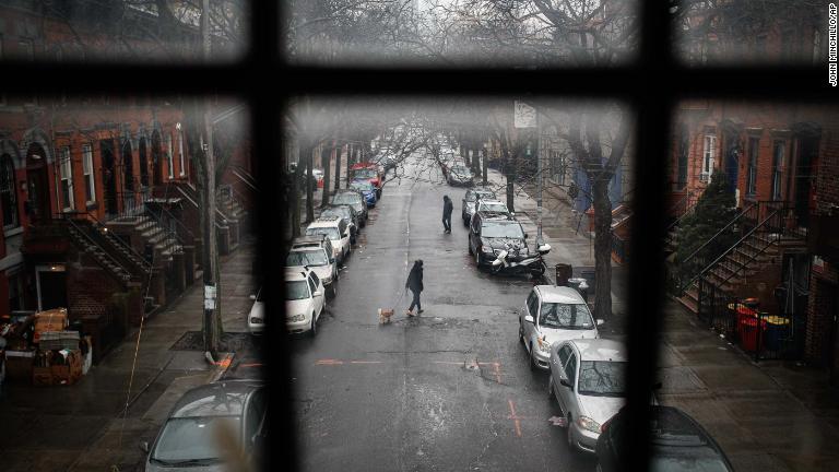 人けのない街中で犬を散歩させる人＝１７日、ニューヨーク/John Minchillo/AP