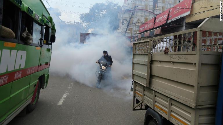 消毒剤の中を走るバイク＝１３日、インド/Channi Anand/AP