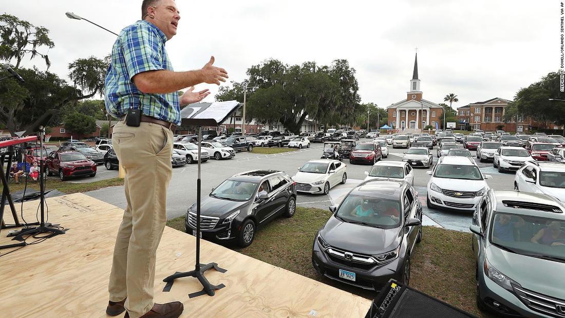 車に乗った人々に語り掛ける聖職者=フロリダ州/Stephen M. Dowell/Orlando Sentinel via AP