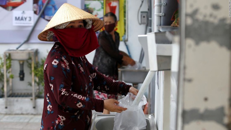 プラスチック袋いっぱいにコメを詰める女性＝１１日、ホーチミン市/Yen Duong/Reuters