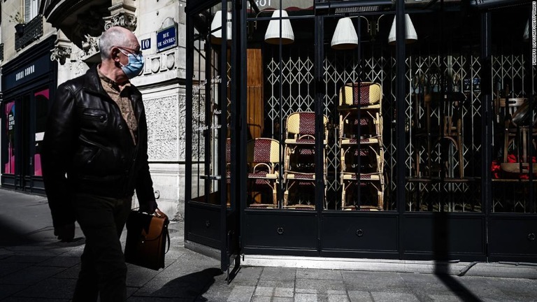 閉鎖されたレストランの前を歩く男性＝１５日、パリ/Philippe Lopez/AFP/Getty Images
