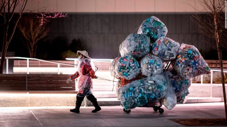 大量の再生可能プラスチックを乗せたカートを引いてニューヨークの街路を歩く女性/JOHANNES EISELE/AFP/Getty Images