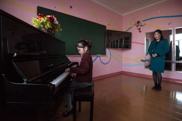 平壌郊外にある孤児のための学校でピアノの指導を受ける少女/Ed Jones/AFP via Getty Images