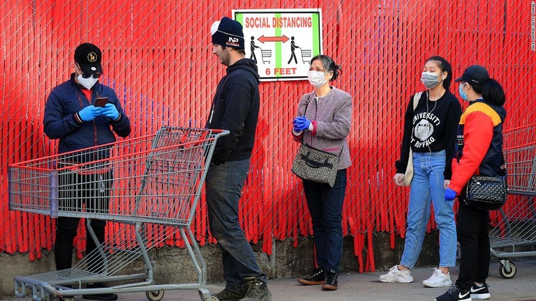 マスクを着け、間隔をあけて店舗の列に並ぶ人々/Mike Lawrie/Getty Images
