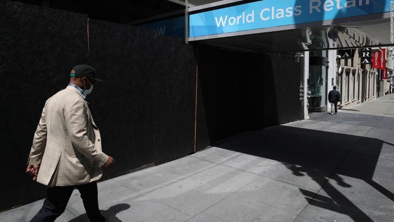 小売店の並ぶ通りをマスクを着けて歩く男性/Justin Sullivan/Getty Images