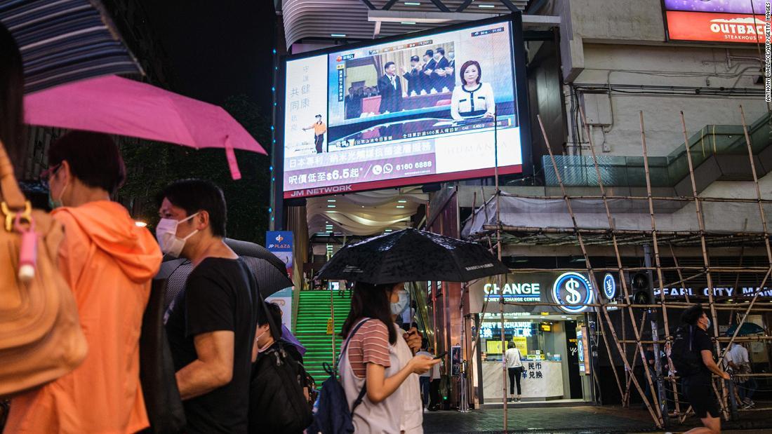 歩行者が全国人民代表大会の様子を伝えるスクリーンの下を歩く様子=21日/Anthony Wallace/AFP/Getty Images