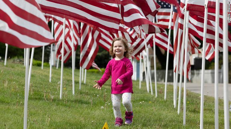 旗の下を歩く子ども＝２３日、マサチューセッツ州/Michael Dwyer/AP