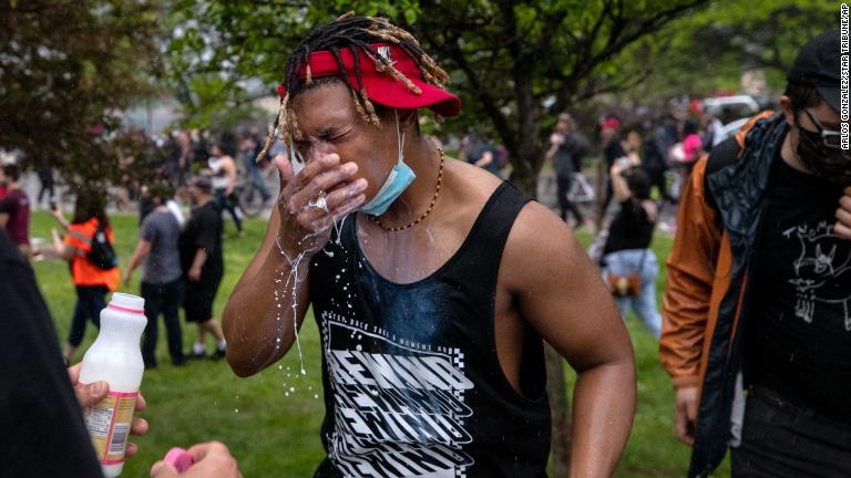 催涙ガスを浴び、牛乳で鼻や口をすすぐデモ参加者/arlos Gonzalez/Star Tribune/AP