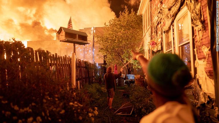 抗議デモの現場近くに住む住民。ホースやバケツの水で自宅を火災から守る/Mark Vancleave/Star Tribune/Getty Images