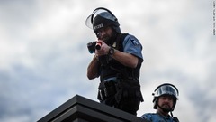 警察署の施設の屋上に立ち、投射物の射出装置を構える警官