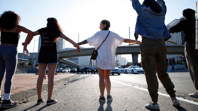ロサンゼルスの路上で手をつなぐ抗議デモ参加者ら/Dania Maxwell/Los Angeles Times/Getty Images