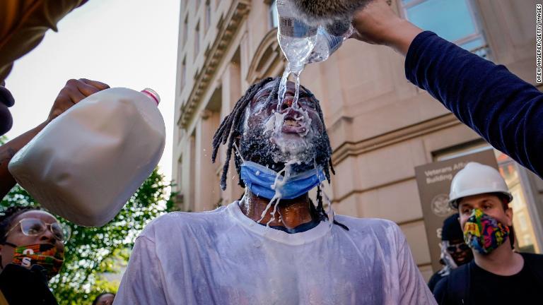催涙スプレーをかけられて水と牛乳で顔を洗うデモ参加者＝６月１日、ワシントン/Drew Angerer/Getty Images