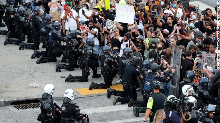デモ参加者とともに膝をつく警官＝６月１日、ジョージア州アトランタ/Curtis Compton/Atlanta Journal-Constitution via Sipa USA