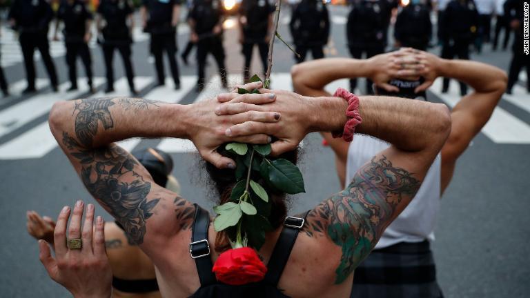 警官隊の前で膝をつくデモ参加者＝６月３日/John Minchillo/AP