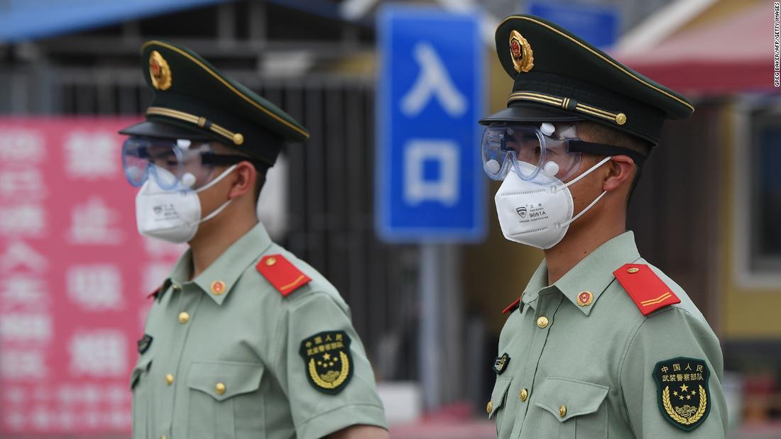 マスクとゴーグルを装着した準軍事警察が市場の入り口で警戒に当たる様子＝１３日、北京/Greg Baker/AFP/Getty Images