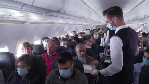 機内で乗客に消毒用のウェットティッシュを配る客室乗務員/CNN