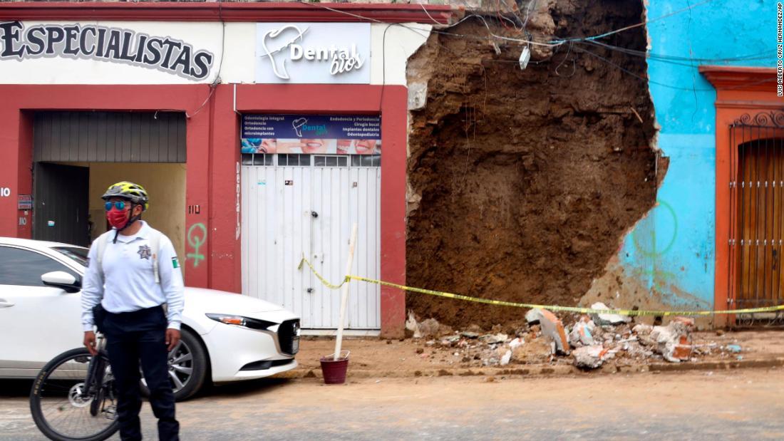 一部が崩壊した建物の前に立つ警察官/Luis Alberto Cruz Hernandez/AP
