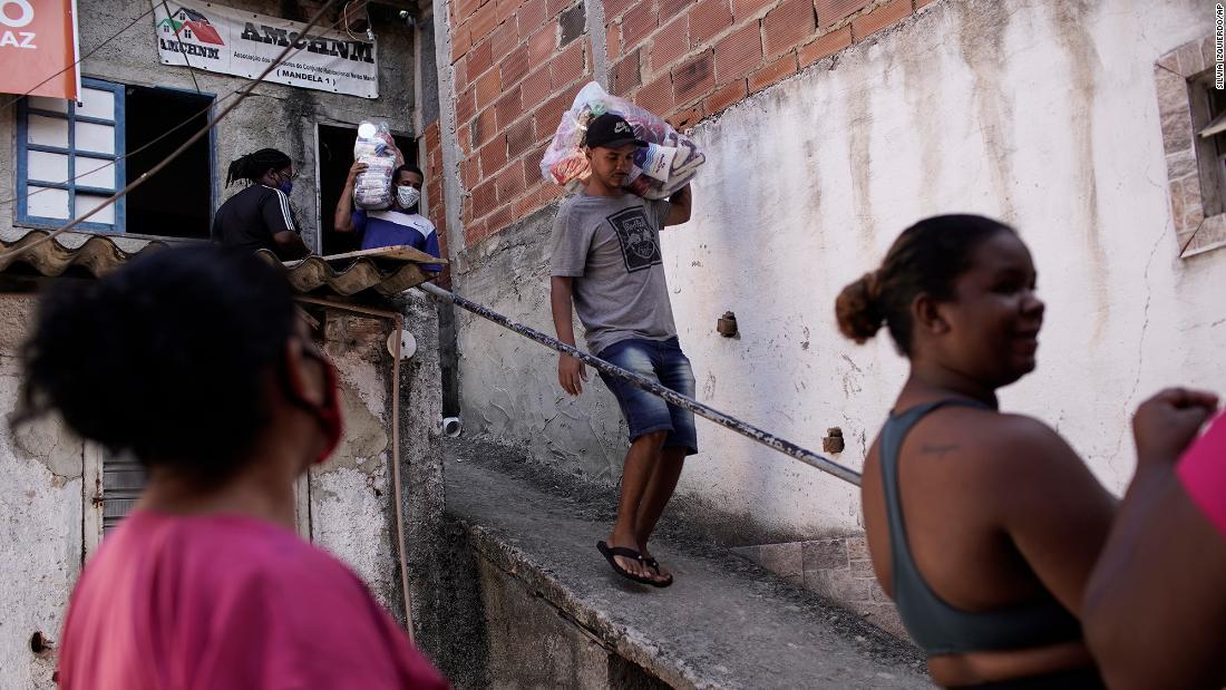 コロナ禍で非政府組織（ＮＧＯ）から支給された食料品を運ぶ住民＝４月２１日、リオデジャネイロのスラム街/Silvia Izquierdo/AP