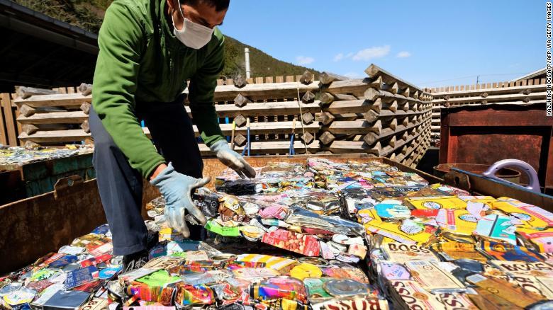 缶を圧縮した薄板を積み上げる上勝町の住民/KAZUHIRO NOGI/AFP/AFP via Getty Images
