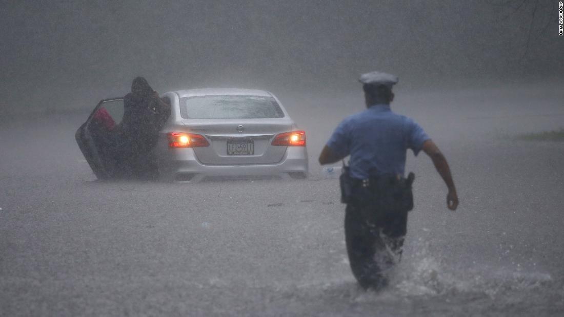 豪雨で車が立ち往生し警察官が現場に向かった＝米ペンシルベニア州フィラデルフィア/Matt Slocum/AP