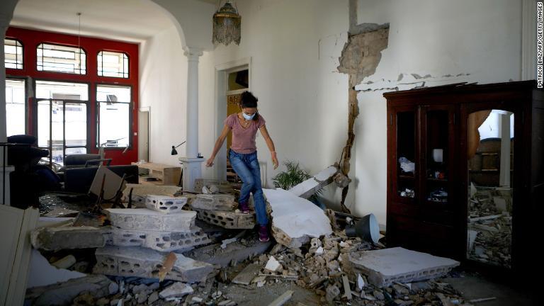 がれきに埋もれた室内を歩く女性/Patrick Baz/AFP/Getty Images