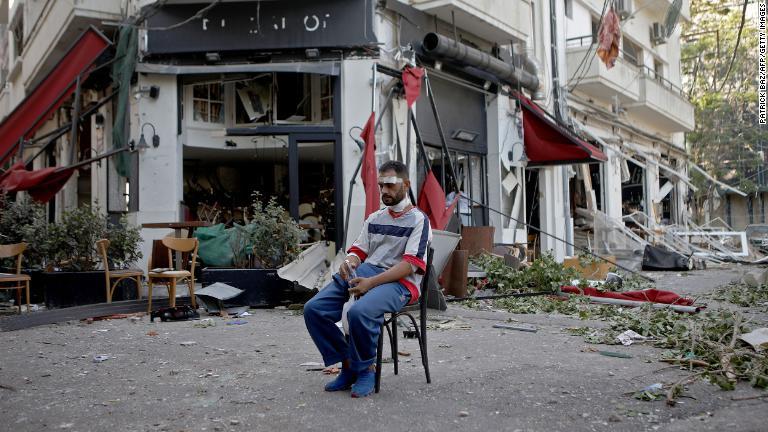 レストランの隣で椅子にすわる負傷した男性/Patrick Baz/AFP/Getty Images