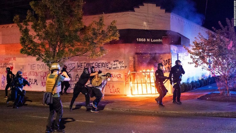 警察関連の建物に放火するデモ隊を排除する警官ら＝２９日未明、ポートランド/Nathan Howard/Getty Images