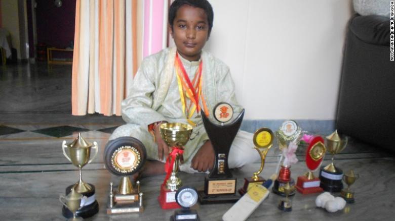 数学の大会で獲得した数々のトロフィーと写真に収まる１０歳のころのバヌ氏/Neelakantha Bhanu Prakash