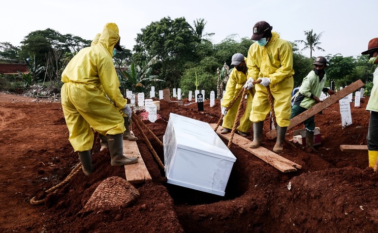ジャカルタの墓地で感染予防の防護具を身につけ埋葬を行う作業員/Anton Raharjo/Anadolu Agency/Getty Images