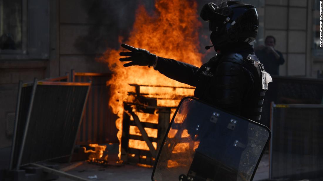 火の近くに立つ機動隊員＝１２日、パリ/ALAIN JOCARD/AFP/AFP via Getty Images