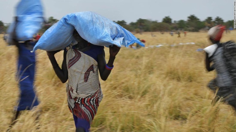 南スーダンのアヨドで世界食糧計画した投下した食糧を運ぶ村の人々/TONY KARUMBA/AFP/Getty Images
