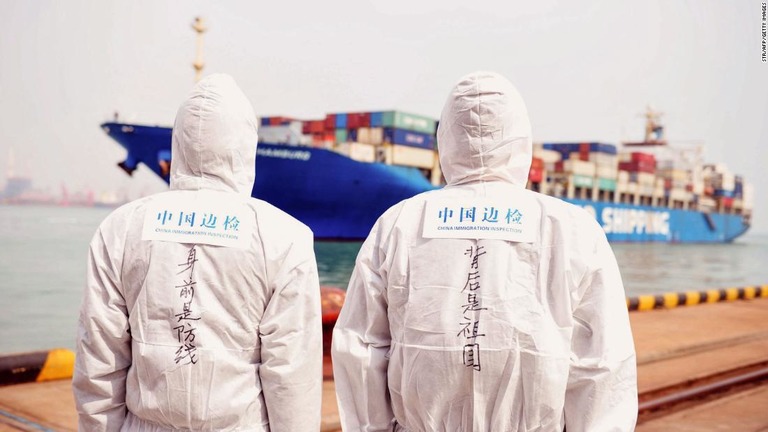 防護服に身を包んだ中国の当局者が、港湾で貨物船を見守る様子＝３月３１日、山東省青島/STR/AFP/Getty Images