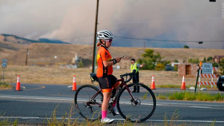 自転車を止めて写真を撮る女性＝コロラド州ボルダー/David Zalubowski/AP