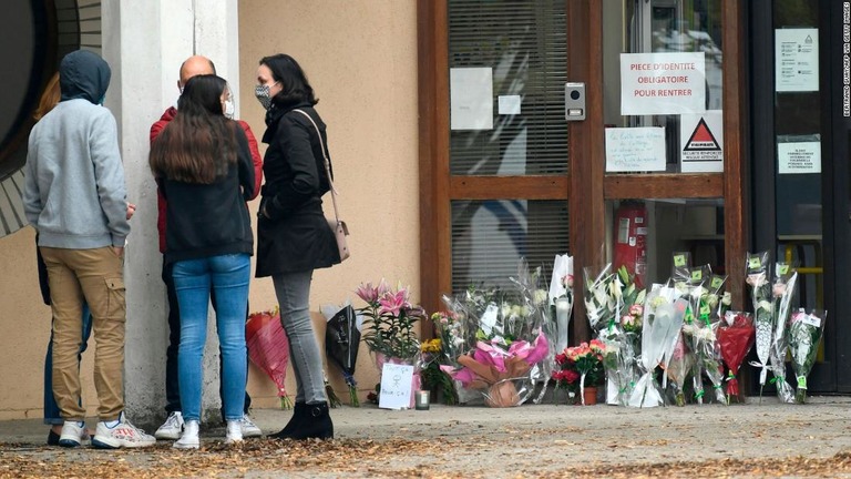 殺害された教員が勤務していた学校。入り口には花がたむけられ、人々が集まっている/BERTRAND GUAY/AFP via Getty Images